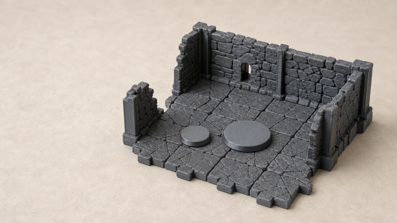 A modular tabletop dungeon terrain piece made of 3D-printed plastic, showing textured stone-like floor tiles and three upright walls with visible layer lines. Two round bases of different sizes sit on the floor, demonstrating scale. The terrain is unpainted gray and placed on a light surface, with no labels, text, or miniatures present.